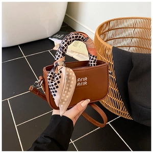 Dettaglio della mini borsa marrone con manico avvolto da foulard in seta e logo