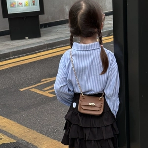 Gros plan d'un mini sac bandoulière marron en cuir grainé avec fermoir rotatif doré et chaîne
