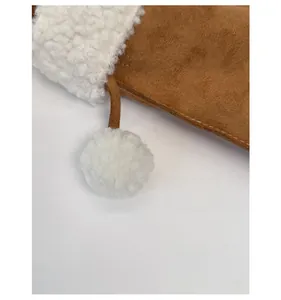 Detail of faux suede handbag with white faux fur trim and decorative plush pom-pom