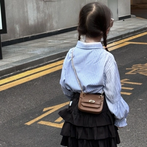 Vue de dos d'une fille avec chemise rayée, jupe à volants et mini sac à chaîne brun