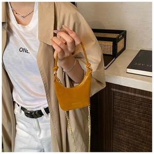 Gros plan d'un mini sac jaune gingembre avec chaîne dorée porté par un mannequin