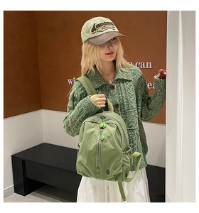 Close-up of bean green nylon backpack featuring a minimalist design and a teardrop zipper pull