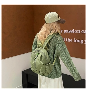 Detail view of water-resistant light green nylon backpack featuring side drawstring pockets