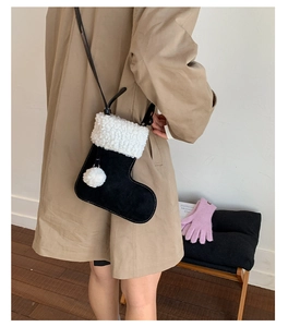Detail of a Christmas stocking shaped black suede crossbody bag with white faux fur trim