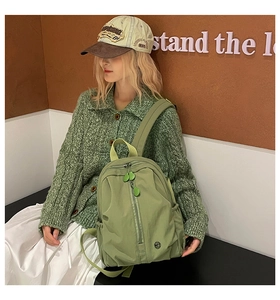Detail of avocado green nylon backpack featuring unique leaf-shaped rubber zipper pulls