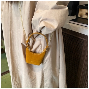Détail du mini sac à main jaune gingembre avec chaîne dorée et poignée ronde rigide