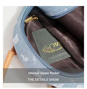 Detail view of the interior zipper pocket in denim bag with VIP card and brown lining