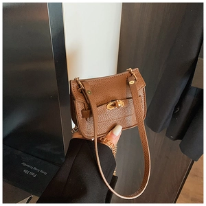 Détail d'un mini sac en cuir litchi marron avec fermoir rotatif doré et bandoulière