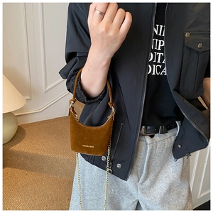 Détail d'un mini sac à main en daim marron avec chaîne dorée et inscription tendance