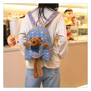 Detail of blue denim backpack with cute plush bear and brown leather accents