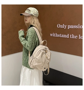 Side view of beige nylon backpack with vertical zipper on model in Korean casual outfit