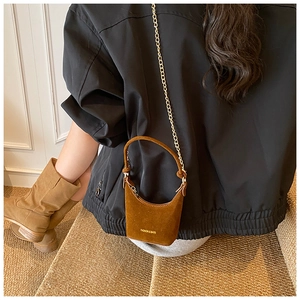 Gros plan d'un mini sac en daim marron avec chaîne dorée et bottines mates assorties