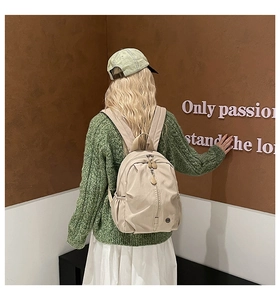 Minimalist beige backpack for children shown on a model in a casual campus setting
