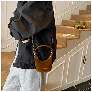 Détail d'un mini sac à main en daim marron pour filles avec une bandoulière en chaîne dorée