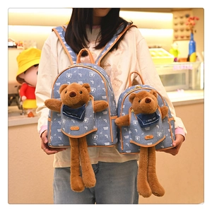 Detail showing two sizes of blue denim backpacks with plush bear inserts and leather trim