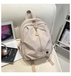 Detail of beige nylon backpack with vertical zipper and functional headphone port