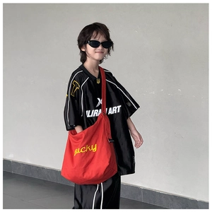 Vue latérale enfant portant un grand sac bandoulière en toile rouge avec broderie Lucky