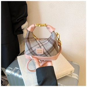 Detail of gray plaid tweed mini bag with pink leather trim and golden metal clasp
