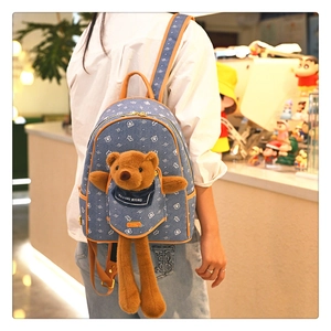 Dettaglio di uno zaino in denim con orsetto di peluche 3D e stampe bianche di orsi