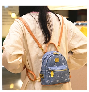 Detail of blue denim backpack featuring white bear prints and gold stud embellishments
