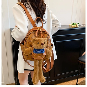 Detail of a brown PU leather backpack with luxury monogram print and 3D plush bear mascot