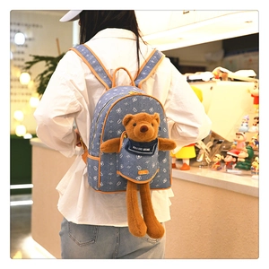 Dettaglio dello zaino in denim blu con orsetto di peluche 3D e stampe di cartoni