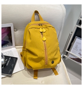 Detail of yellow nylon backpack featuring vertical zip pocket and elastic side pouches