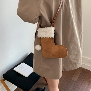 Détail d'un sac botte de Noël en daim marron avec bordure en peluche blanche et pompon