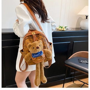 Macro shot of printed PU leather texture and plush bear decoration on women's backpack