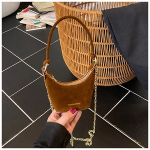 Détail d'un mini sac croissant en daim camel avec chaîne dorée et inscription