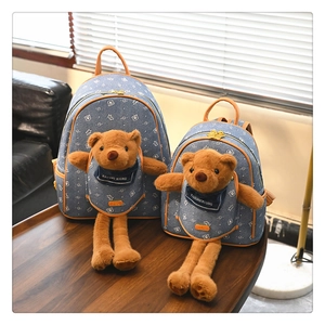 Set zaino in denim blu con orsetto di peluche 3D su un tavolo in legno scuro