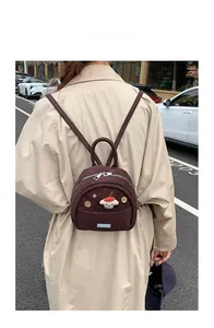 Model wearing a small brown corduroy backpack featuring a cute cartoon doll and wooden buttons