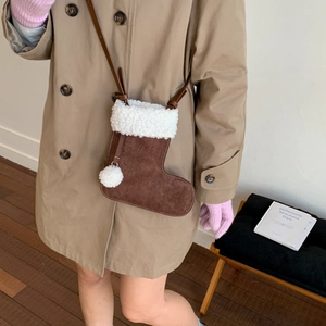 Détail d'un sac bandoulière en daim en forme de botte de Noël avec bordure peluche et pompons
