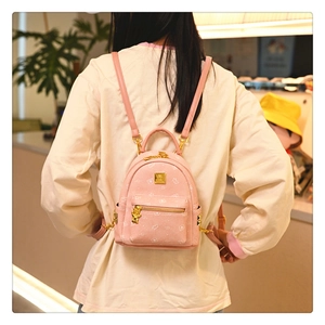 Detail of pink small backpack with cartoon bear prints and golden bear charm pendant