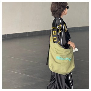 Vue latérale du sac bandoulière en toile vert olive avec broderie Blucky bleue sur modèle