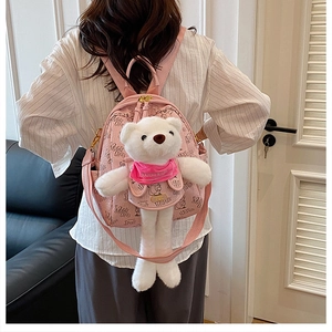 Detail view of the pink leather backpack featuring a large plush bear and black graffiti prints