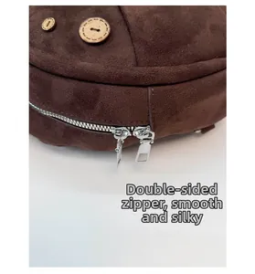 Detail of dark brown faux suede backpack featuring double metal zippers and wooden buttons
