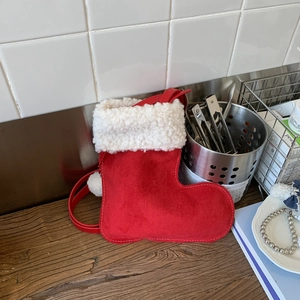 Vue détaillée du sac botte de Noël en daim rouge avec finitions pompons blancs doux