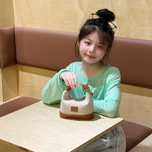 Chic mini leopard canvas handbag with leather base held by a girl in a green sweater