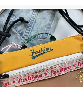 Detail of yellow fabric with Fashion embroidery and colorful woven strap on crossbody bag