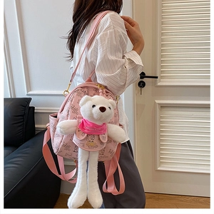Side view of a pink leather backpack with a large white long-legged plush bear charm