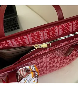 Detailed close-up of smooth gold metal zipper and woven texture on a red festive tote bag
