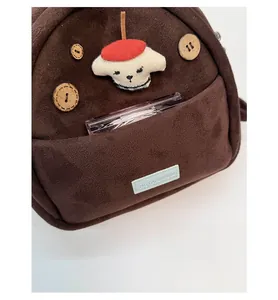 Detail of brown suede backpack front pocket with cute dog patch and wooden buttons