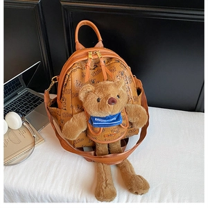 Close-up of brown leather backpack with cartoon patterns and a plush teddy bear ornament