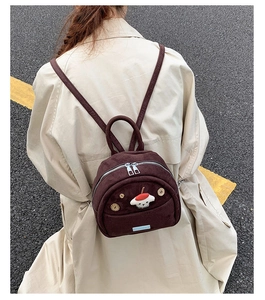 Detailed view of mini brown suede backpack featuring a mushroom patch and zipper closure