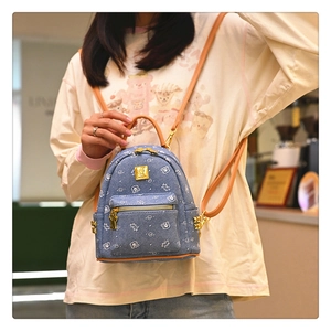 Close-up of a blue denim mini backpack with cute white bear prints and leather straps