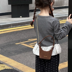 Mini sac à main en daim marron pour filles avec chaîne dorée porté par un jeune modèle