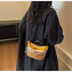 Detail of color-block canvas crossbody bag with Fashion text and floral embroidery