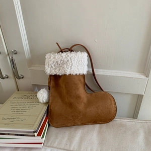 Détail du sac à bandoulière botte de Noël en daim marron avec fourrure blanche et pompons