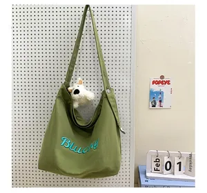 Détail du sac fourre-tout en toile verte avec broderie Blucky et peluche de chien
